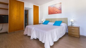 A bedroom with a bed, two bedside tables, a wall-mounted TV, and a door leading to another room. - CANA LALI (Santa Eulalia del Río)