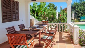 A patio with a dining table, chairs, and a pool in the background. - CANA LALI (Santa Eulalia del Río)