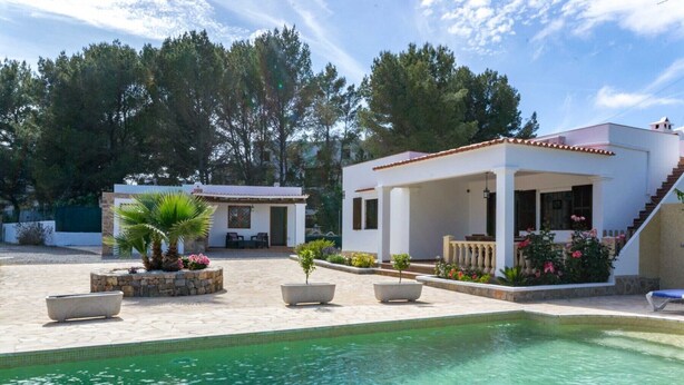 A pool area with a clear pool, two small buildings, and a covered seating area with plants and flowers. - CANA LALI (Santa Eulalia del Río)