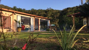 Une maison dotée d’une grande porte vitrée, d’un patio et offrant une vue sur une colline boisée.