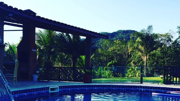 Une piscine avec un toboggan, entourée d’une zone abritée et d’une végétation luxuriante.