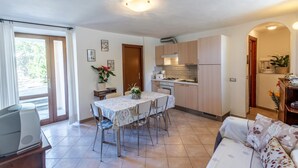 Een knus woongedeelte met een eethoek, kitchenette en een bank.