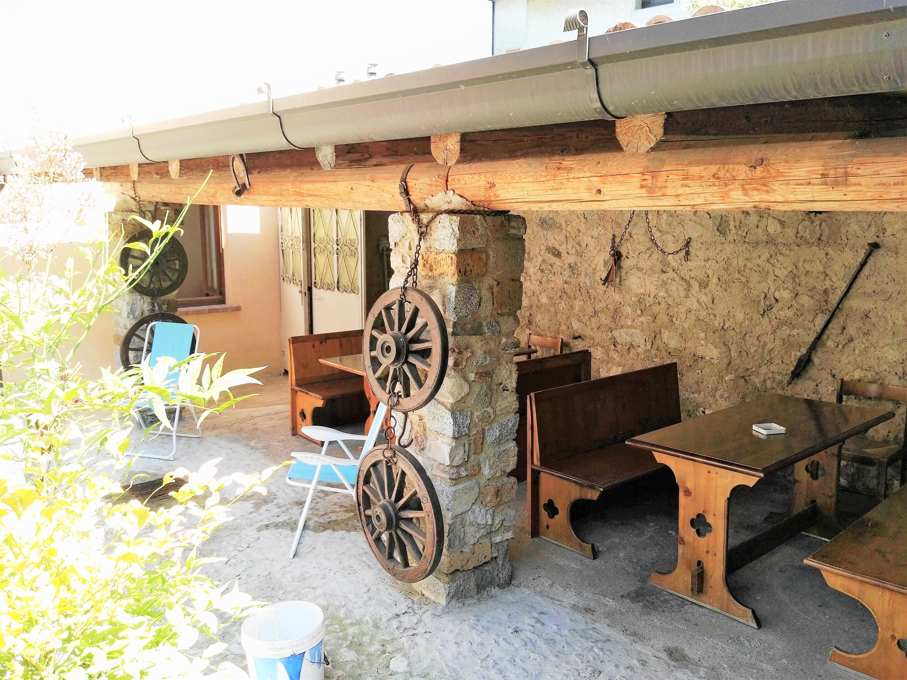 Un espacio al aire libre rústico con mobiliario de madera y un carrusel grande.