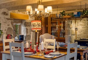 A dining area with a wooden table set for a meal, surrounded by stone walls and a chandelier. - Tregadjack Barn, Tregathenan, Near Porthlevan , Cornwall (Helston)