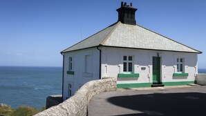 Ein weißes Gebäude mit grünen Verzierungen und einem Schornstein, gelegen am Meer.
