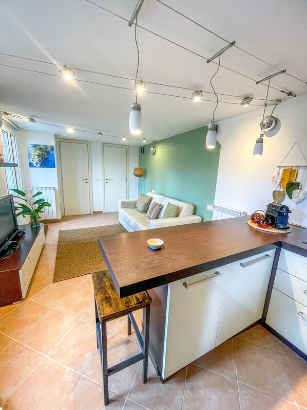A modern kitchen with a central island, white cabinetry, and a dining area with a bench. - Gorgeous modern loft with Jacuzzi view and garden DISCOUNTS MAY/JULY (Santa Margherita Ligure)