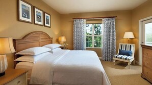 Une chambre à coucher avec un grand lit, des lampes de chevet, une chaise et une commode.