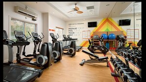 Une salle de sport équipée de tapis de course, de vélos elliptiques et de bancs de musculation.