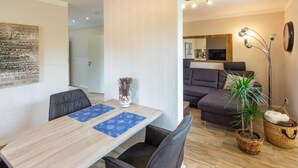 Una sala de estar moderna con un sofá, una mesa de comedor con sillas, una lámpara de pie y una planta en maceta.