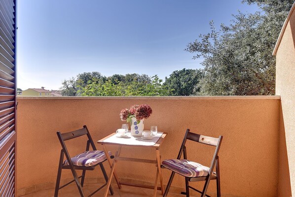 A balcony with two wooden chairs, a small table, and a vase with flowers. - Just 100 Meters to the beach with WiFi and A/C (Medulin)