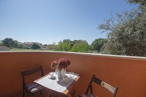 A terrace with a table set for two, a vase with flowers, and a view of the surrounding landscape. - Just 100 Meters to the beach with WiFi and A/C (Medulin)