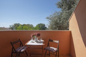 A small outdoor balcony with a table set for two, two chairs, and a vase with flowers. - Just 100 Meters to the beach with WiFi and A/C (Medulin)