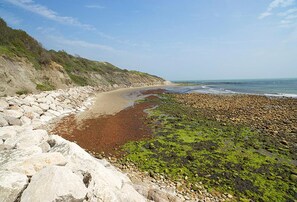 A coastal beach with a rocky shoreline, a sandy beach, and a view of the ocean.