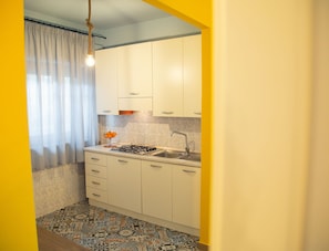 A compact kitchen with white cabinets, a gas stove, and a sink.