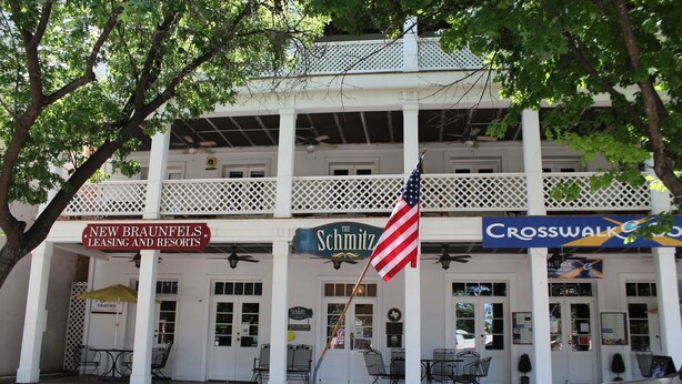 Un edificio con diversi cartelli, tra cui 'New Braunfels Leasing and Resorts', 'The Schmitz' e 'Crosswalks'.