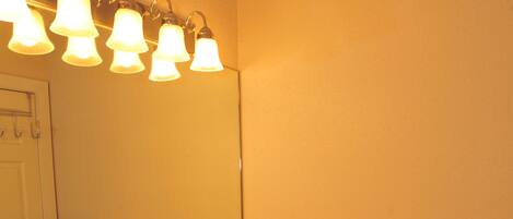 A bathroom with a double sink, a mirror, and a light fixture above the mirror.