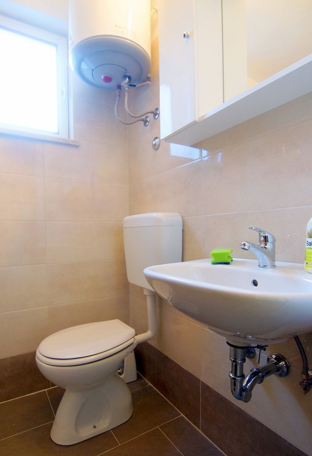 Ein Badezimmer mit Toilette, Waschbecken und Duschkopf.