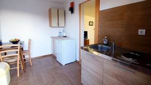 Eine kleine Küche mit einem weißen Kühlschrank, einem Spülbecken und Holzschränken.