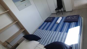 Quarto com cama, cadeira, televisão e um quadro na parede.