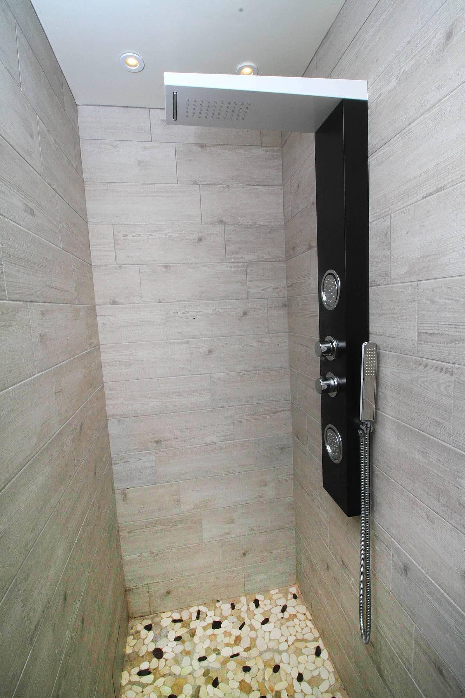 A modern shower with a control panel, a handheld showerhead, and a built-in rain showerhead.