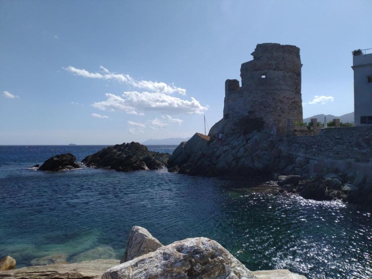 A coastal view with a historic stone tower and rocky shoreline.