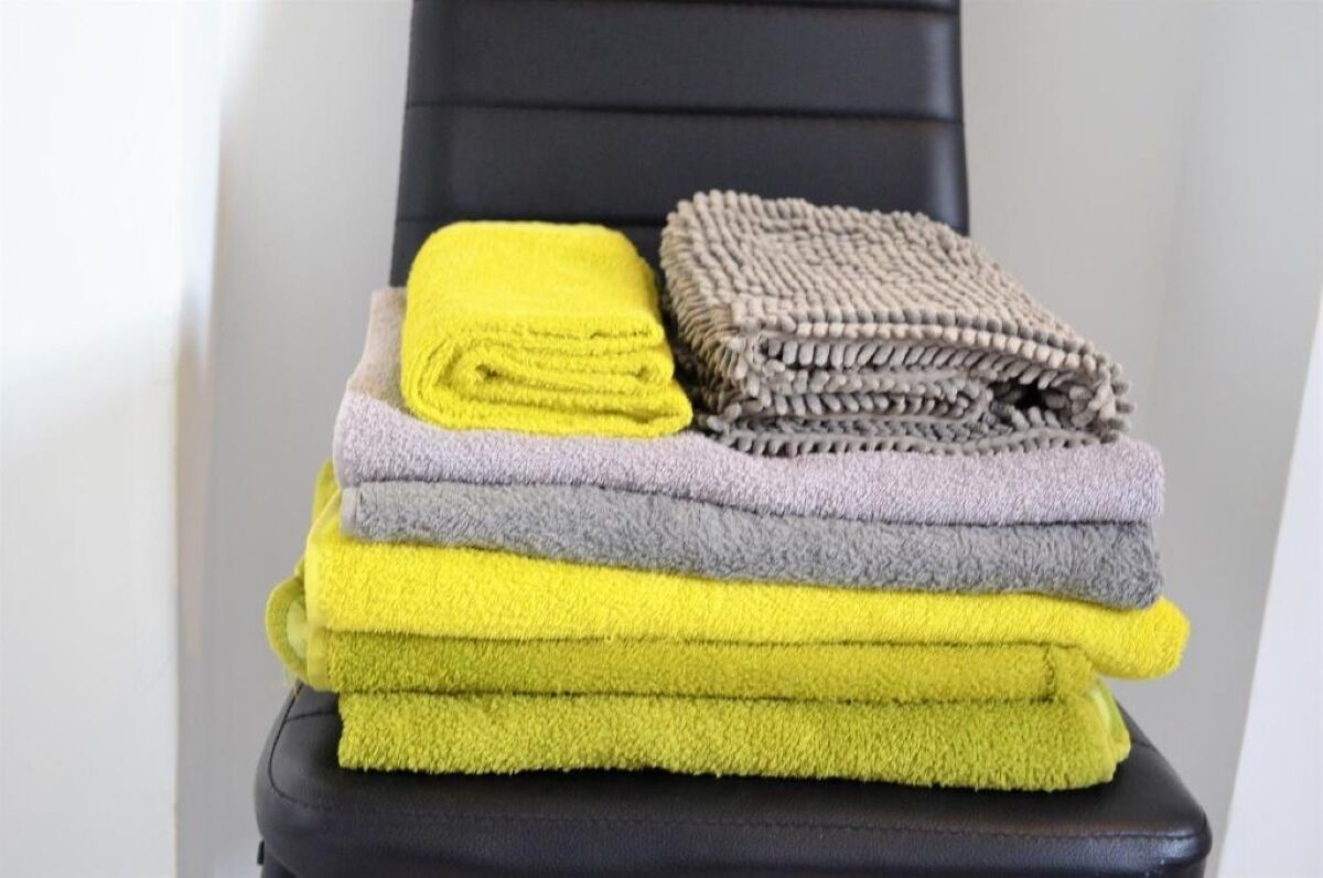 A stack of folded towels in various colors on a chair.