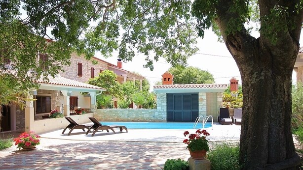 A pool area with lounge chairs, a stone building, and a tree. - Apartment with pool, air conditioning, WiFi (Krnica)