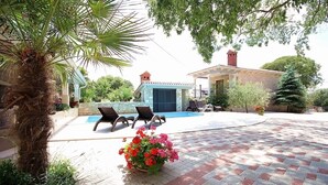A pool area with lounge chairs, a palm tree, and a brick patio. - Apartment with pool, air conditioning, WiFi (Krnica)