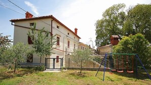 A two-story house with a balcony, a swing set, and a small garden area. - Apartment with pool, air conditioning, WiFi (Krnica)