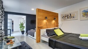 Et moderne soveværelse med en stor seng, sengeborde, et skrivebord og en potteplante.
