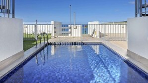 A swimming pool with a clear view of the sky and a modern building in the background. - Beachside Paradise - Ocean Views, Central Position (Manly)