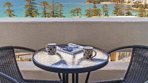 A balcony with a table, two chairs, and two patterned mugs. - Beachside Paradise - Ocean Views, Central Position (Manly)