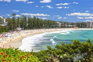 A beach with a sandy shore, waves, and a clear sky. - Beachside Paradise - Ocean Views, Central Position (Manly)
