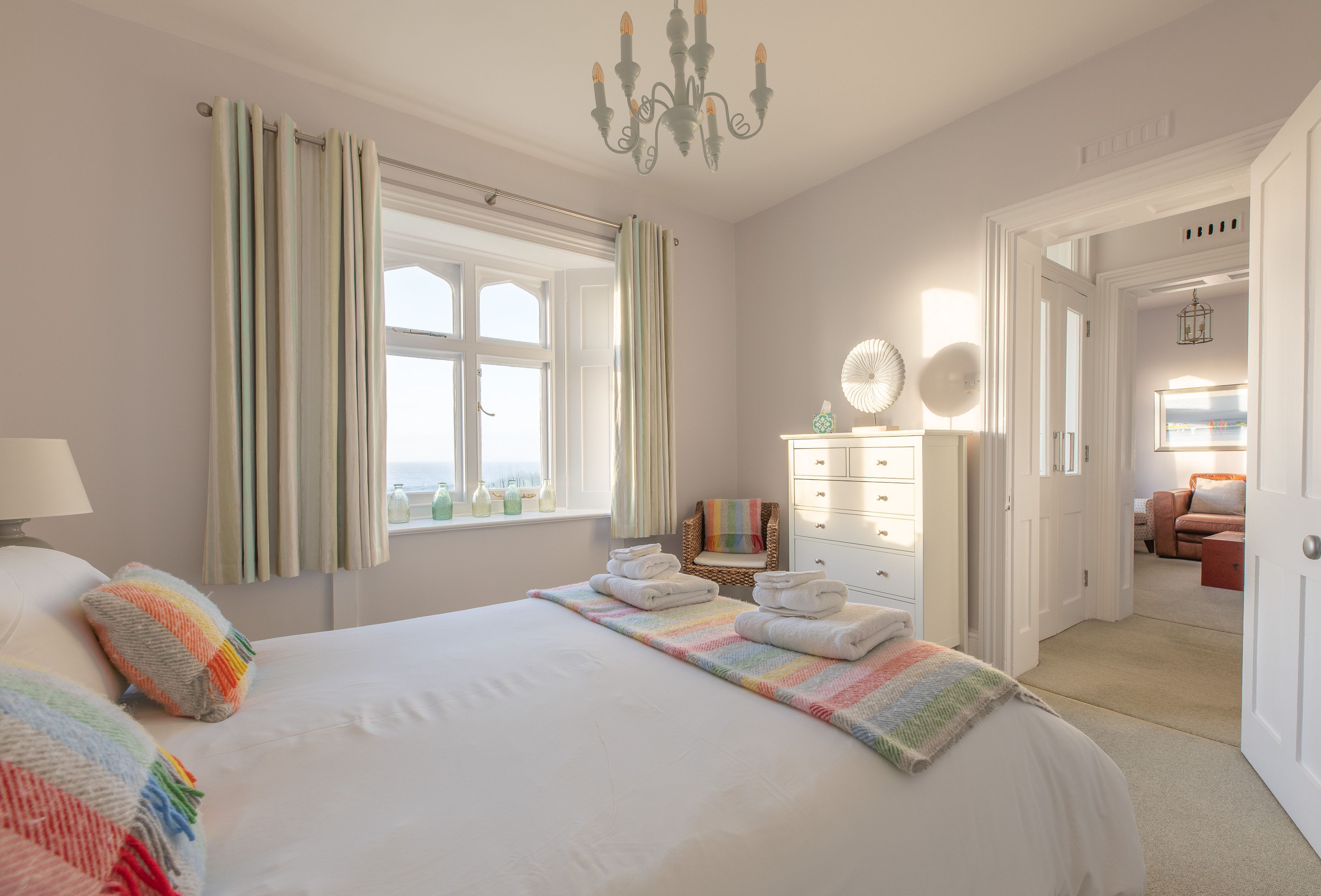 Habitación de hotel con una cama grande, una silla, un aparador y vistas al exterior.