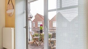 A balcony with a sliding glass door, a white radiator, and two wooden chairs with a potted plant. - High-quality and bright: The upstairs apartment offers the fine and sat (Carolinensiel)