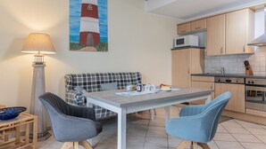 A modern kitchen with wooden cabinets, a dining table, and a sofa. - High-quality and bright: The upstairs apartment offers the fine and sat (Carolinensiel)
