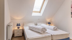A bedroom with a skylight, two bedside tables with lamps, a double bed with rolled towels, and a radiator. - High-quality and bright: The upstairs apartment offers the fine and sat (Carolinensiel)
