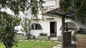 A courtyard with a small tree, a covered seating area, and a building with arched windows and a door. - OliLer s House&Garden Zona Centro (Guanajuato)