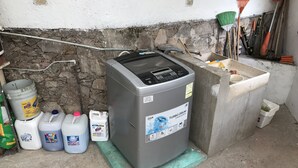 A laundry machine with detergent bottles and cleaning supplies. - OliLer s House&Garden Zona Centro (Guanajuato)