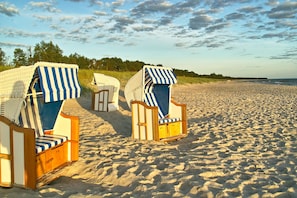 To strandstole med stribede betræk på en sandstrand.
