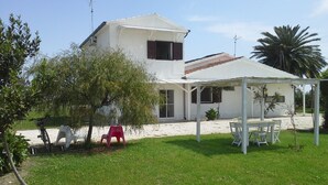 A house with a covered patio area, a lawn, and a tree.