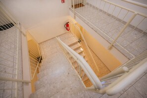 Ein mehrstöckiger Innenbereich mit Feuerlöscher, Metallgeländern und Fliesenböden.
