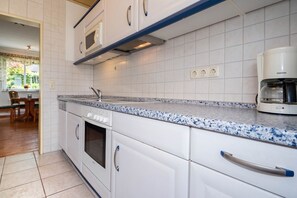 Eine Küche mit weißen Schränken, einer Arbeitsplatte aus Granit, einem Einbauofen und einer Siemens-Kaffeemaschine.