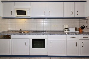 A kitchen with white cabinets, a microwave, a coffee maker, and a dishwasher. - Cozy vacation apartment in Ahlbeck with terrace - only 100 m to the Baltic Sea (Seebad Ahlbeck)