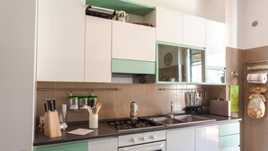 A kitchen with white and green cabinets, a gas stove, a sink, and various utensils. - My Rental Homes - Il Giardino di Ravello with ample private garden and sea view (Ravello)
