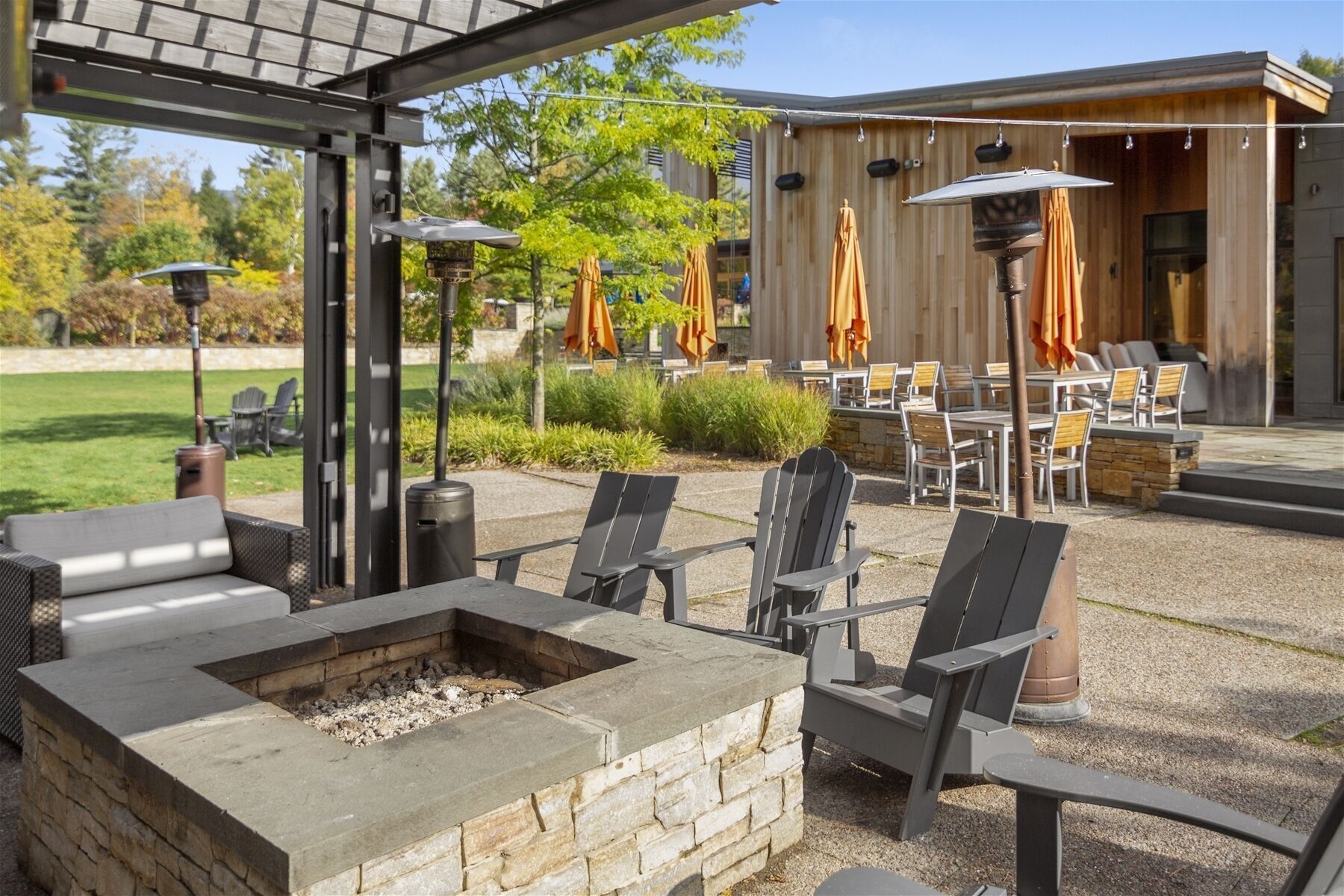 An outdoor patio with Adirondack chairs, a fire pit, and umbrellas.
