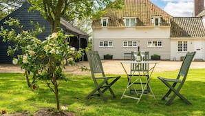 A two-story house with a tiled roof, a front lawn with a table and chairs, and a tree with flowers. - River View, Aldeburgh (Aldeburgh)