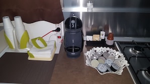 A kitchen with a coffee maker, stacked cups, and a basket of coffee pods. - semi-detached holiday home center (Reggio Calabria)