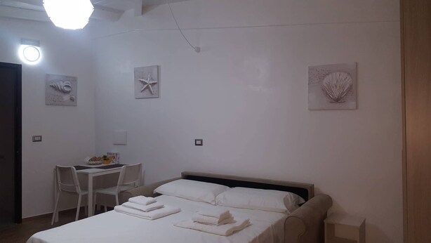 A bedroom with a bed, a desk, and chairs. There are wall decorations and a light fixture. - semi-detached holiday home center (Reggio Calabria)