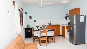 A compact kitchen with a dining table, chairs, a refrigerator, and a stove. - Studio Kin.  Close to Beaches, diving and Island Attractions. Paradise found. (Cozumel)
